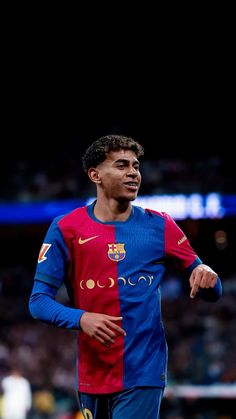 a soccer player in blue and red uniform running on the field with his hand out