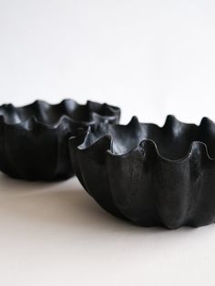 two black bowls sitting on top of a white table