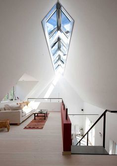 an open living room with white walls and wooden flooring that has a skylight in the ceiling