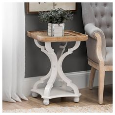 a white table with a plant on top and a chair in the corner behind it