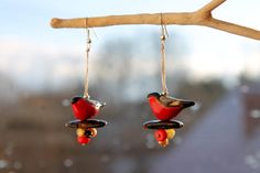 two red birds hanging from hooks on a tree branch