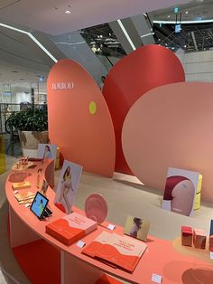 an orange table with pictures and cards on it in front of a large pink sculpture