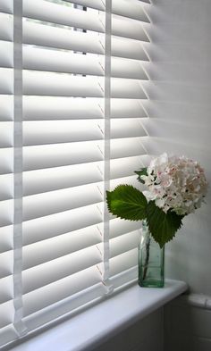 a vase filled with flowers sitting on top of a window sill next to a white wall