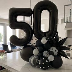 the balloon number 50 is surrounded by black and white balloons in front of a kitchen counter