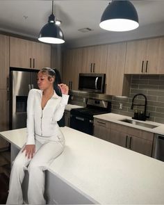 a woman sitting on top of a counter in a kitchen