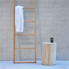 a wooden ladder leaning up against a wall next to a white towel and a bottle