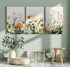 three paintings on the wall in a room with a chair and vase full of flowers