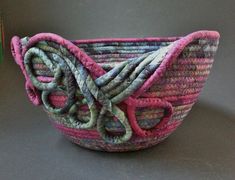 a pink and green woven basket sitting on top of a table