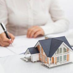 a model house sitting on top of a table next to a calculator and pen