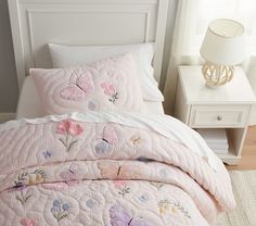 a bed with pink and white quilted bedspreads