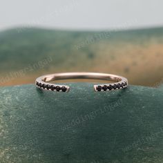 an open ring with black diamonds sitting on top of a green surface