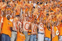 a group of young men and women wearing orange shirts holding up their hands in the air