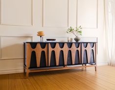 a wooden sideboard with two vases sitting on top of it next to a window