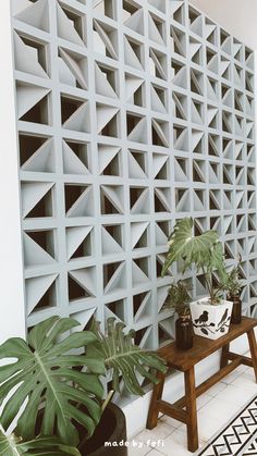 a room with some plants and a bench in front of a wall that has geometric designs on it