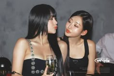 two beautiful young women standing next to each other holding wine glasses in front of their faces