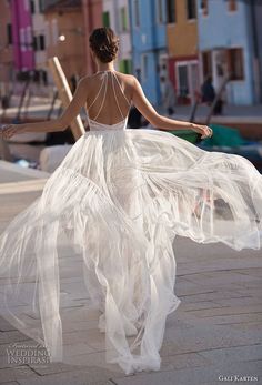 a woman in a white dress is walking down the street with her back to the camera