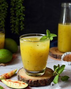 a glass filled with liquid sitting on top of a table next to sliced apples and limes