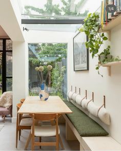 a dining room table and bench with plants in the window