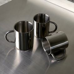 two stainless steel mugs sitting on top of a counter