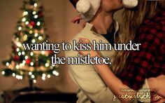 a man and woman kissing in front of a christmas tree with the words kiss under the mistle