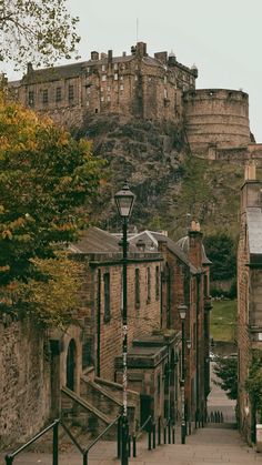 an old street with stone buildings and a castle in the background