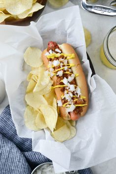 a hot dog with toppings and potato chips