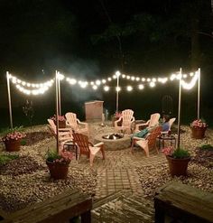 an outdoor fire pit surrounded by chairs and string lights