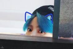 a person with blue hair and cat ears on their head looking through a computer screen