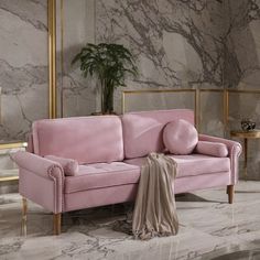 a pink couch sitting on top of a marble floor next to a potted plant