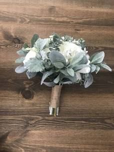 a bridal bouquet with white flowers and greenery on a wooden table, top view