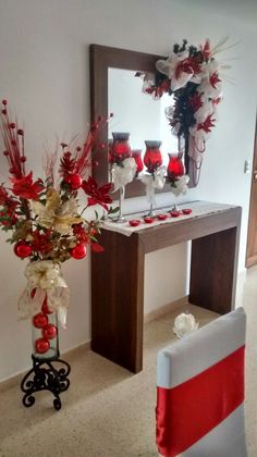 a vase filled with red and white flowers next to a mirror on top of a table