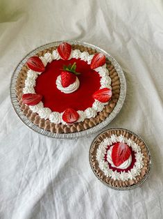 two pies with strawberries on them sitting on a table