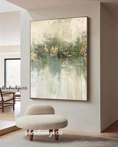 an abstract painting hangs on the wall above a white chair and ottoman in a modern living room