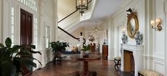 a living room with wooden floors and white walls, along with potted plants on either side of the fireplace