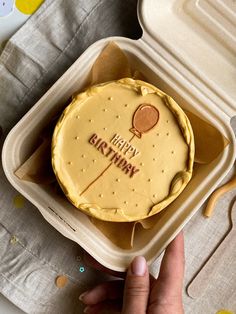 a person holding a birthday cake in a container