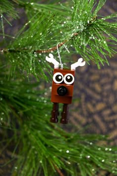 a christmas ornament hanging from a pine tree with eyes and antlers on it