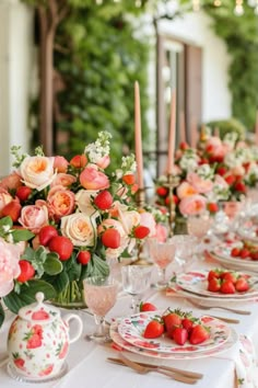 the table is set with pink and white flowers, candles, and strawberrys in vases