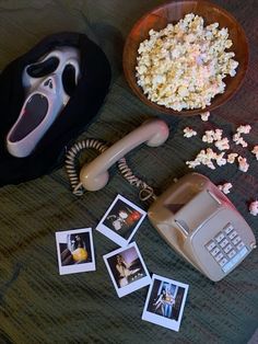 an old phone, bowl of popcorn and other items on a bed with a mask next to it