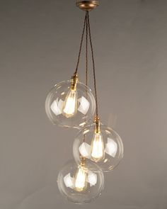 three clear glass globes hanging from a brass chandelier