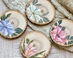 four pieces of wood with painted flowers on them sitting on a blanket next to a teddy bear