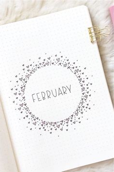 a spiral notebook with the word february written on it next to a pen and pencil