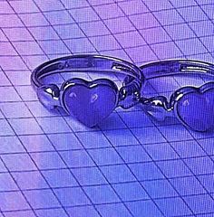 two heart shaped rings sitting next to each other on top of a blue tile floor