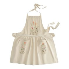 a white apron with flowers on it is hanging from a hook in front of a white background