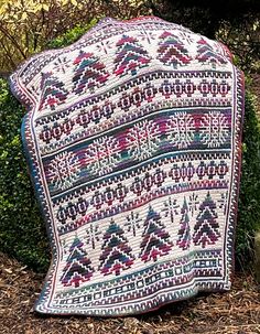 an old blanket is sitting on the ground in front of some bushes and shrubbery