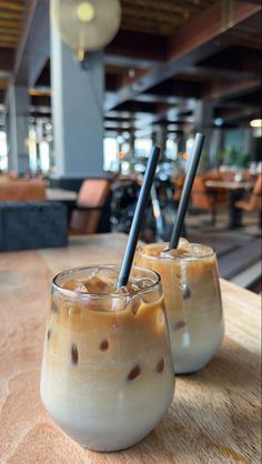 two glasses filled with liquid sitting on top of a wooden table next to each other