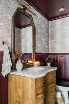 a bathroom with a sink, mirror and candles on the counter in front of it