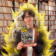 a young man holding up a comic book in front of a library full of books