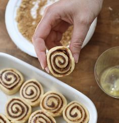 a person is holding a cinnamon roll in front of some other desserts on a table