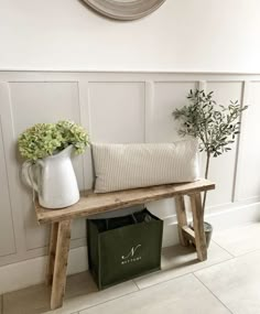 a wooden bench sitting next to a wall with a vase on it and a plant