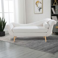 a white couch sitting on top of a wooden floor next to a potted plant